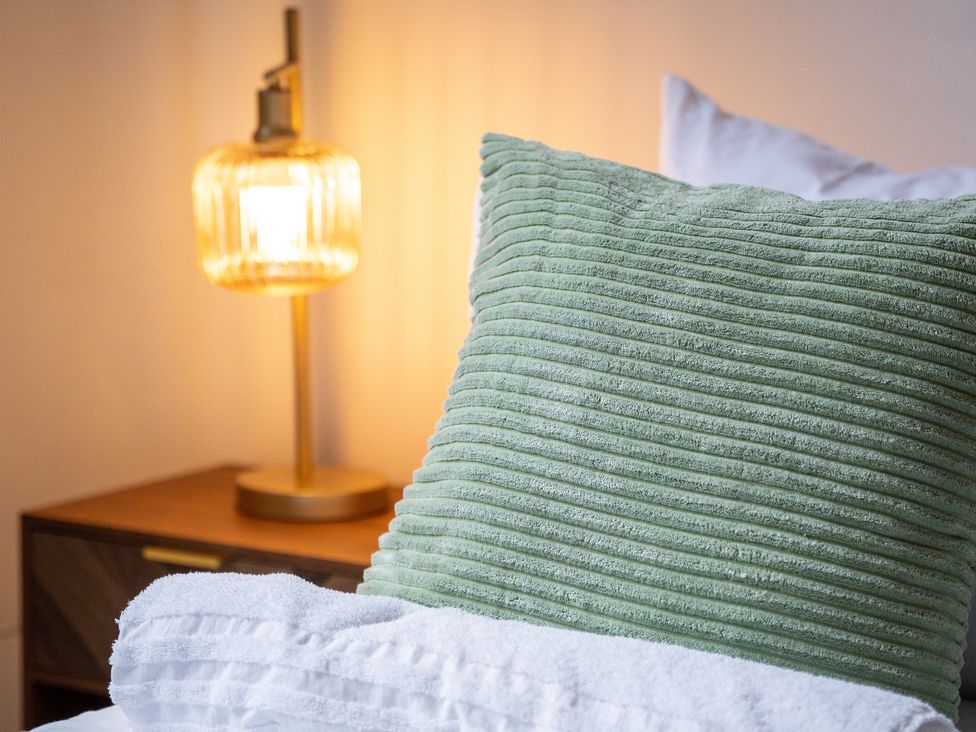 A pillow and lamp on a bedside table at The Gilder Birmingham City Apartment Birmingham