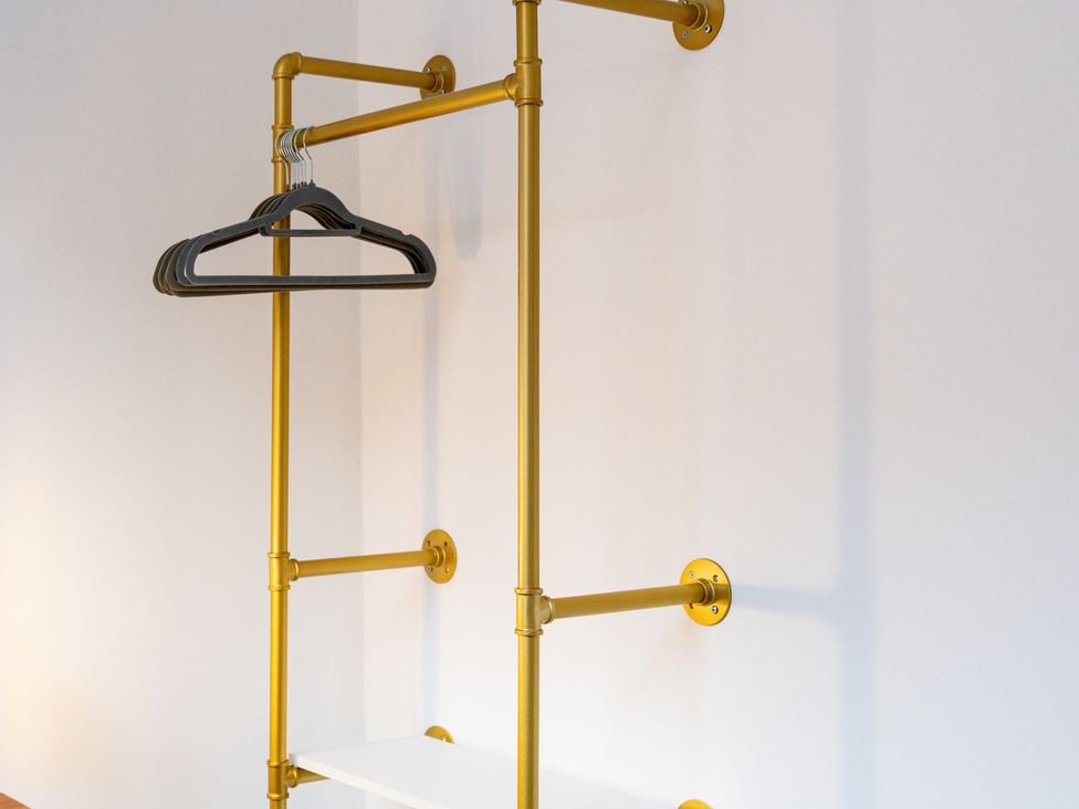 A clothes rack with hangers and a shelf at The Gilder Birmingham City Apartment Birmingham