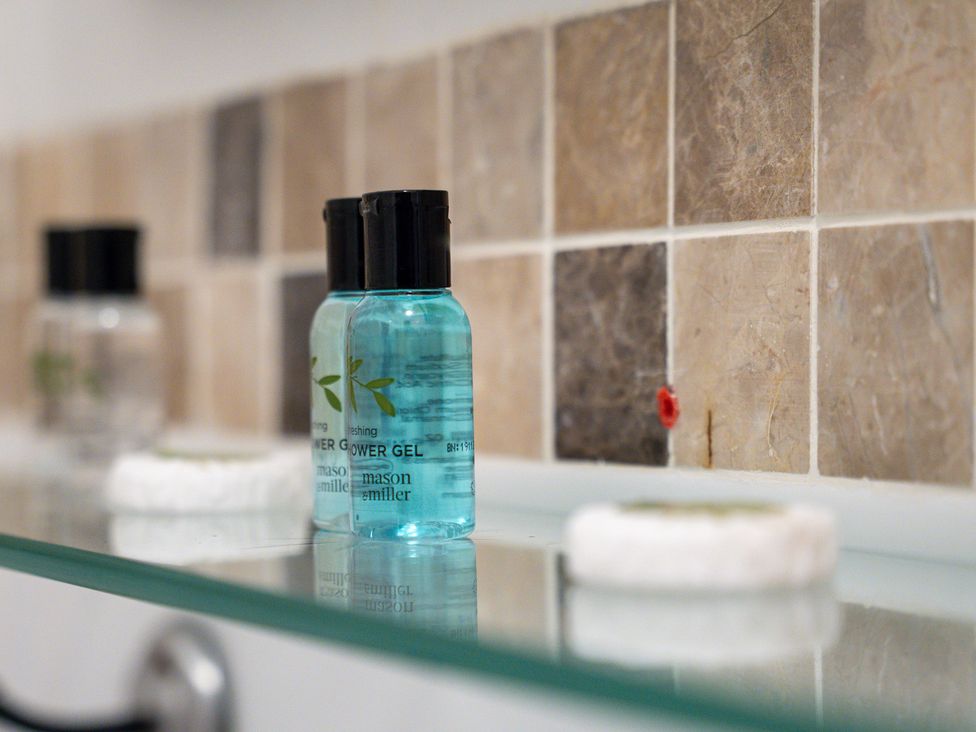 A shower gel and soap dish on a glass shelf in a bathroom at The Gilder Birmingham City Apartment Birmingham