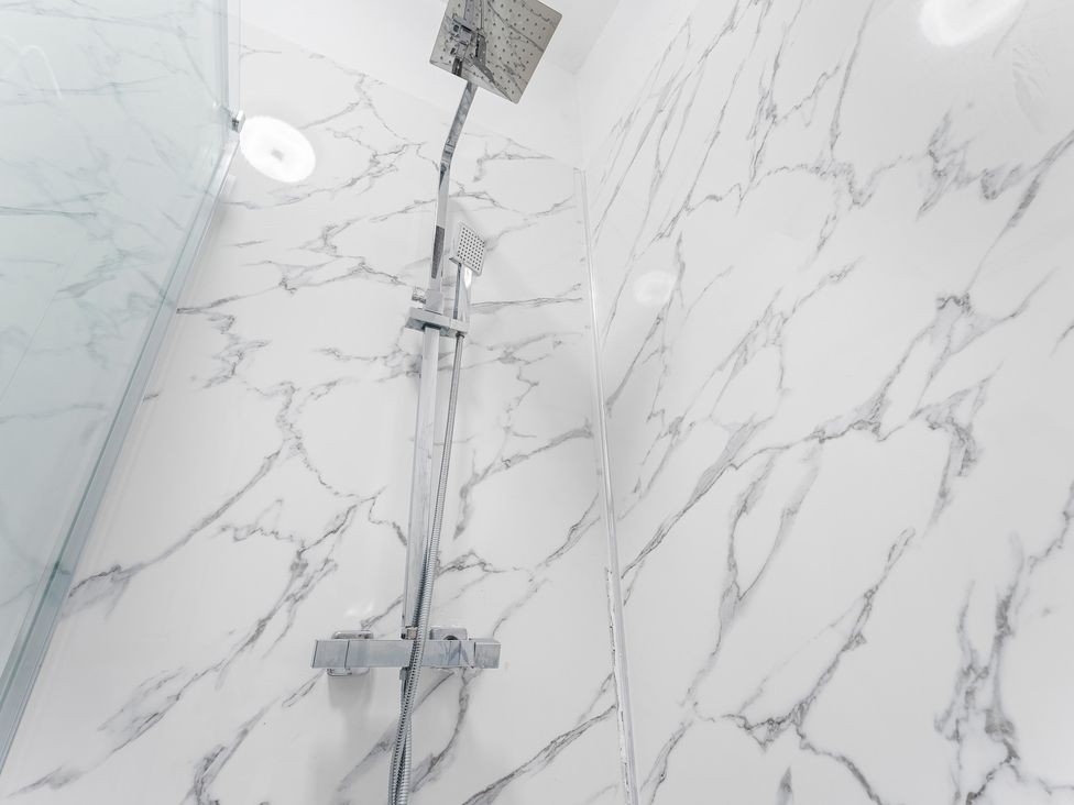 A shower with marble walls and fixtures at The Gilder Birmingham City Apartment