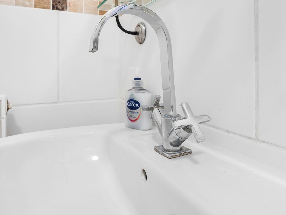 A sink with a tap and liquid soap dispenser at The Gilder Birmingham City Apartment in Birmingham