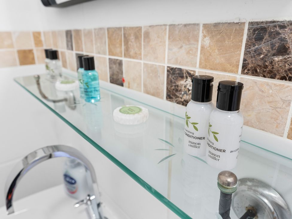 A bathroom shelf with shampoo, conditioner, body wash, and soap at The Gilder Birmingham City Apartment Birmingham