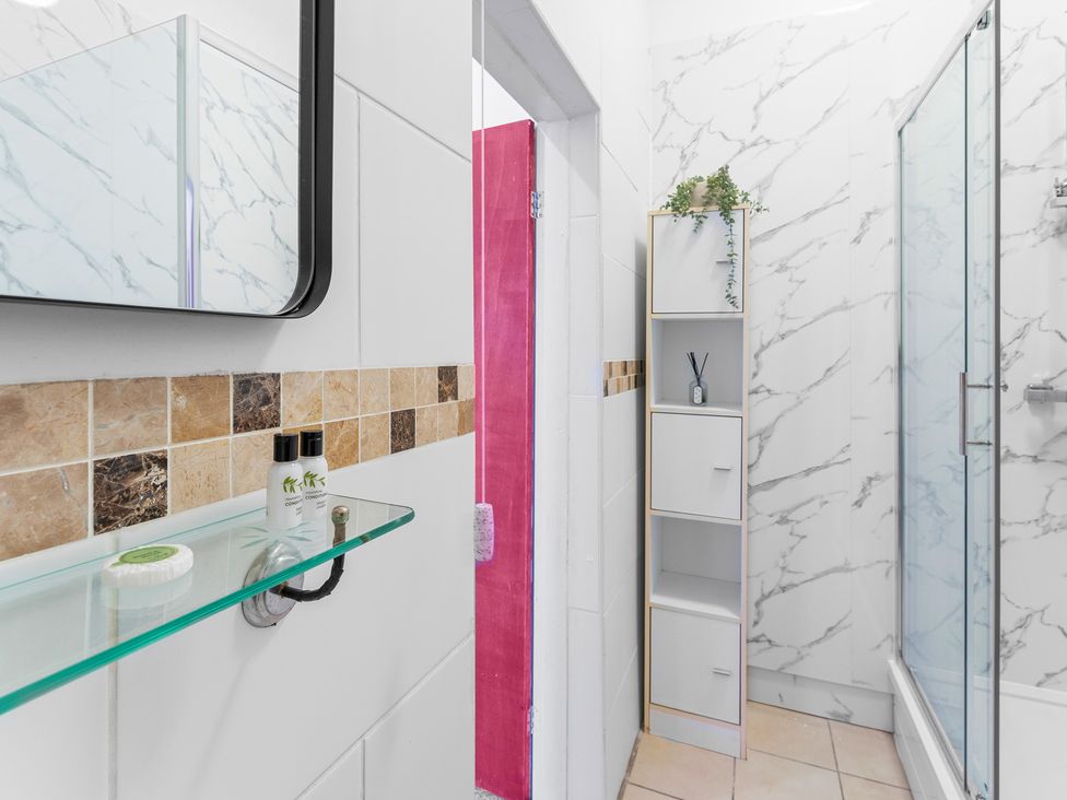 A bathroom with a shower and storage cabinet at The Gilder Birmingham City Apartment