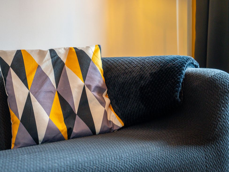A couch with a patterned pillow and a blanket at The Craftsman Birmingham City Apartment in Birmingham