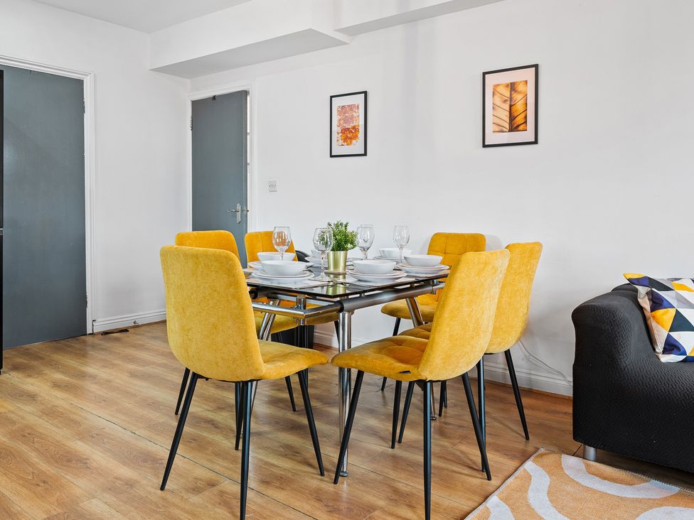 A dining room with a table and yellow chairs at The Craftsman Birmingham City Apartment, Birmingham
