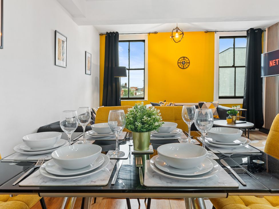 A dining room setup with dishes and glasses at The Craftsman Birmingham City Apartment Birmingham