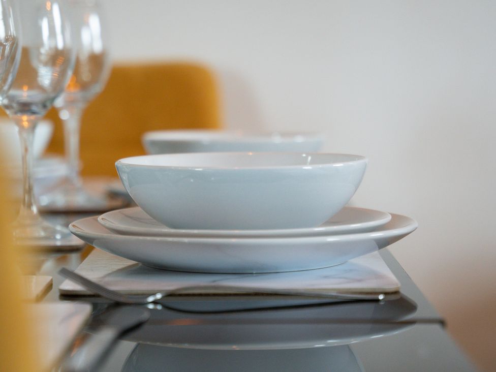 A dining table set with plates and glasses at The Craftsman Birmingham City Apartment Birmingham