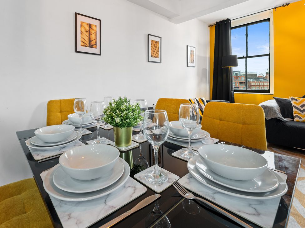 A dining room with a table set for meals at The Craftsman Birmingham City Apartment Birmingham