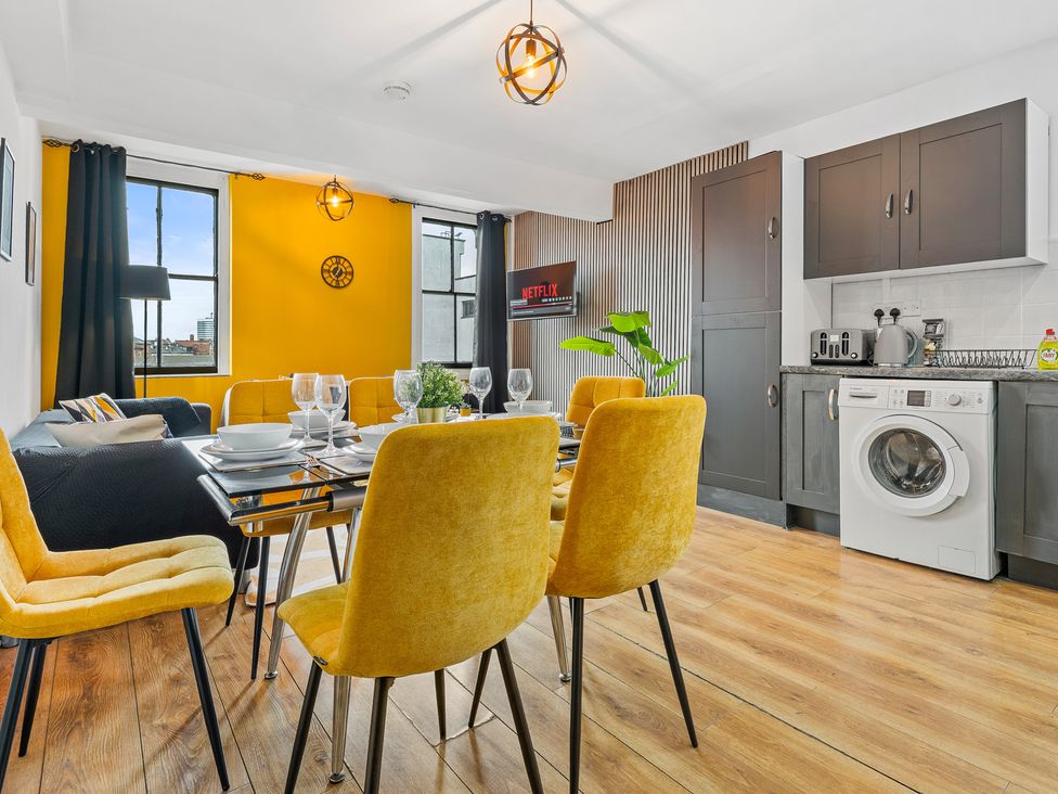 A dining room with a table and yellow chairs at The Craftsman Birmingham City Apartment Birmingham