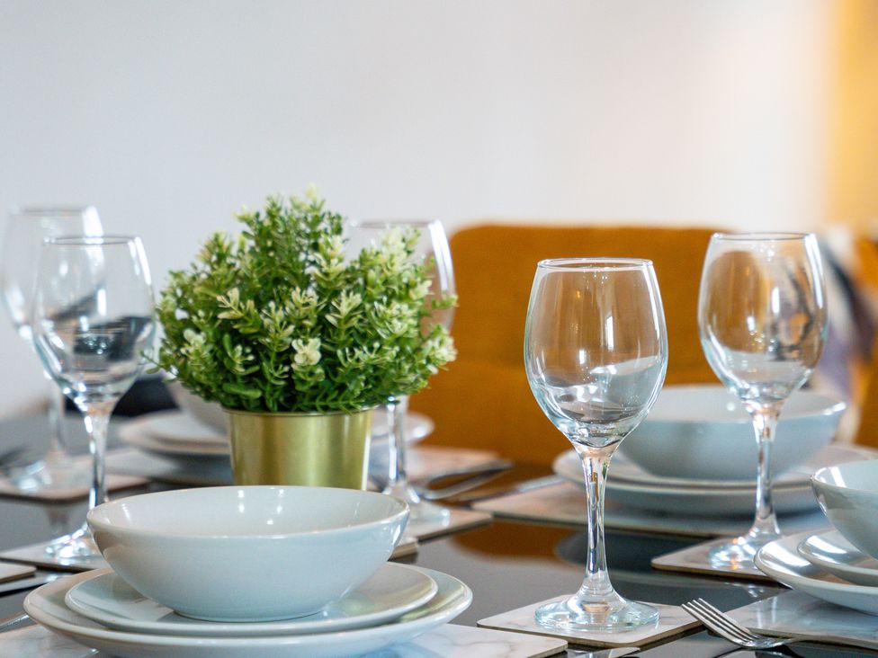 A dining table set with glasses and bowls at The Craftsman Birmingham City Apartment Birmingham
