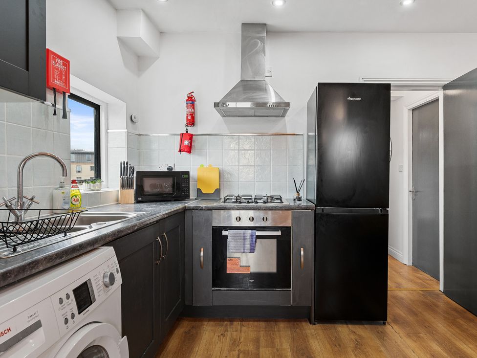 A kitchen with stove, refrigerator and washing machine at The Craftsman Birmingham City Apartment Birmingham