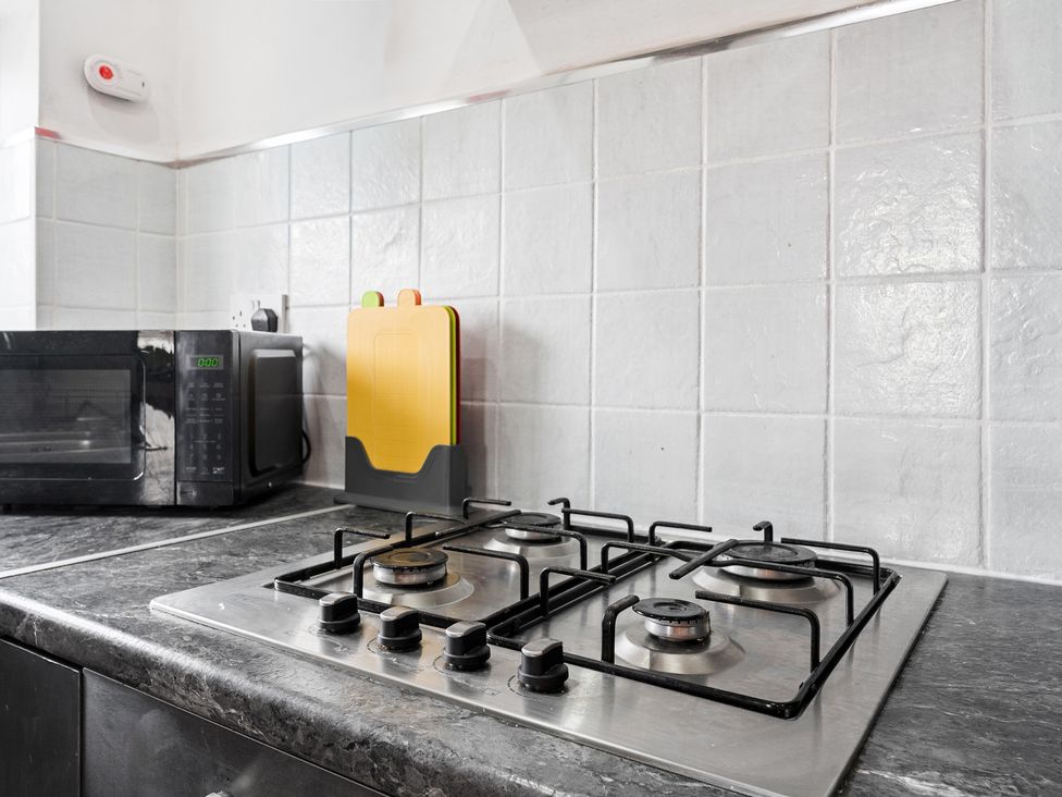 A kitchen with a gas stove and microwave at The Craftsman Birmingham City Apartment Birmingham