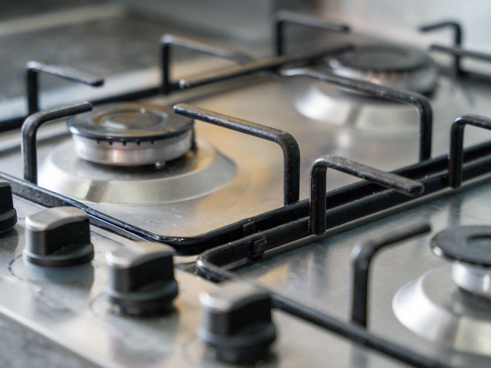 A gas stove with burners and knobs at The Craftsman Birmingham City Apartment Birmingham