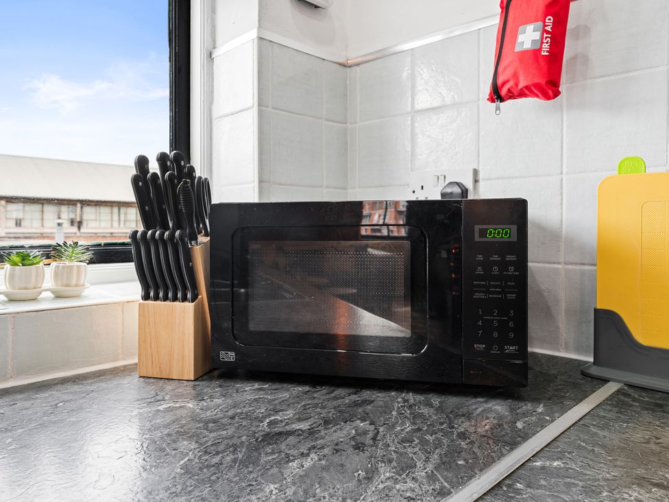 A kitchen with a microwave and knife block at The Craftsman Birmingham City Apartment Birmingham