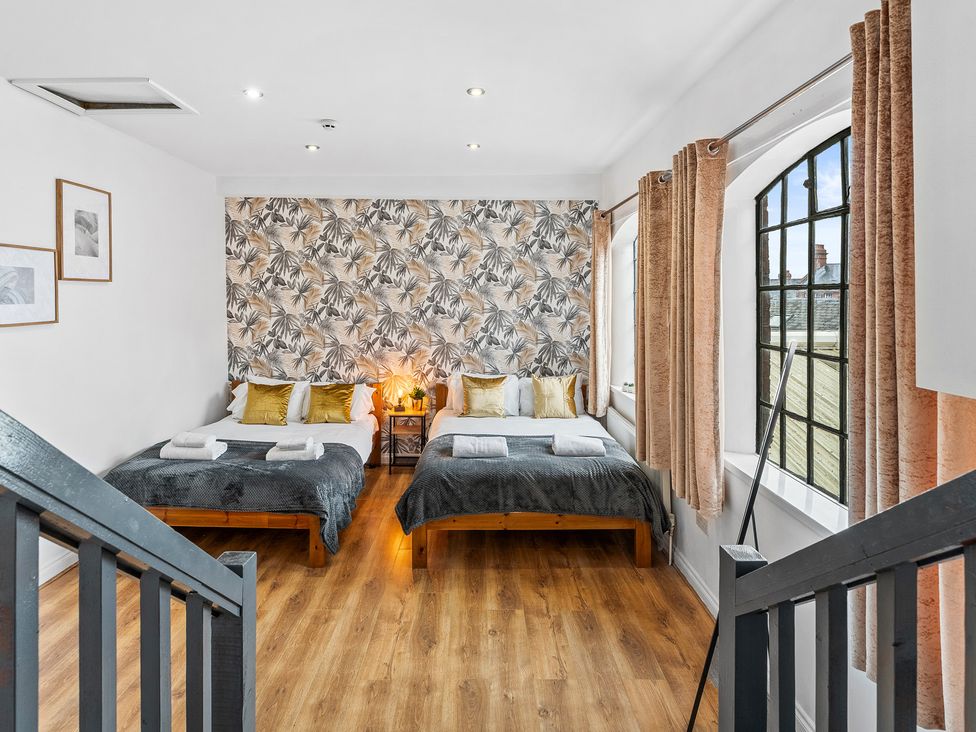 A bedroom with two beds and large windows at The Craftsman Birmingham City Apartment Birmingham