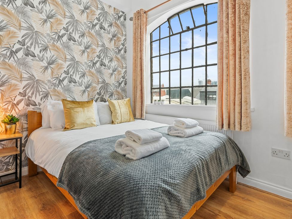 A bedroom with a bed and large window at The Craftsman Birmingham City Apartment Birmingham