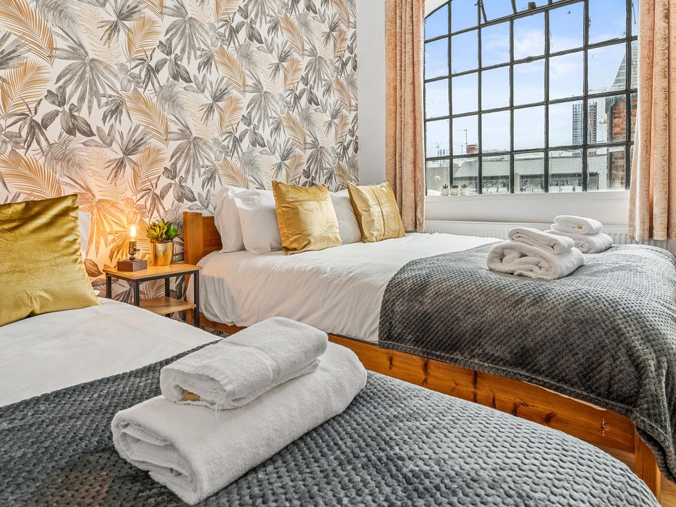 A bedroom with two beds and a large window at The Craftsman Birmingham City Apartment Birmingham