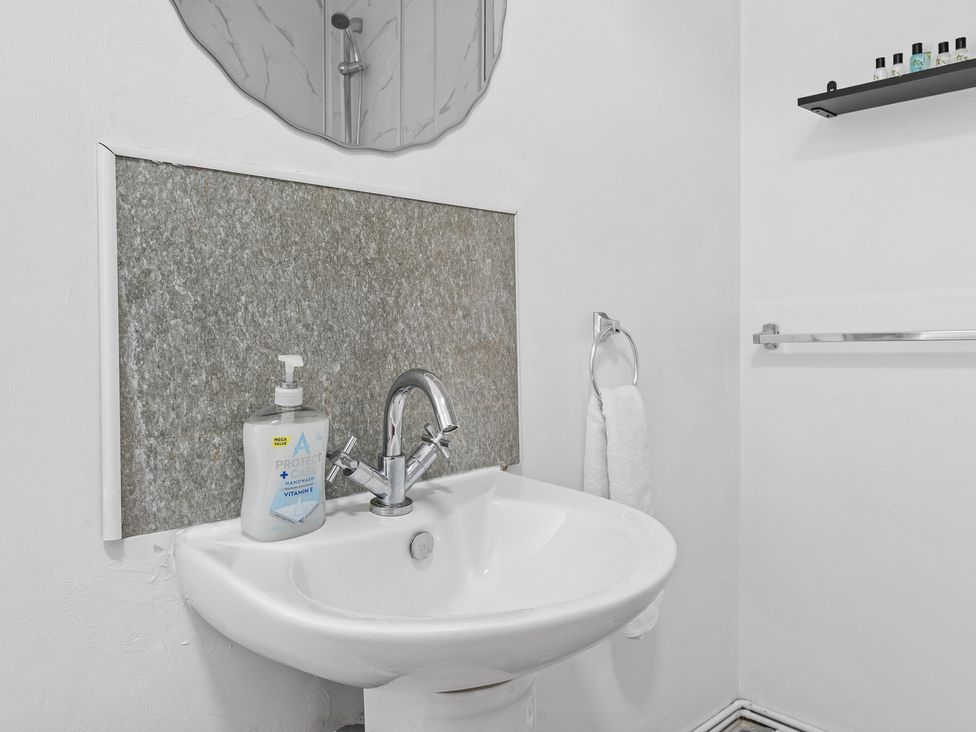 A sink with a mirror and soap dispenser at The Craftsman Birmingham City Apartment Birmingham