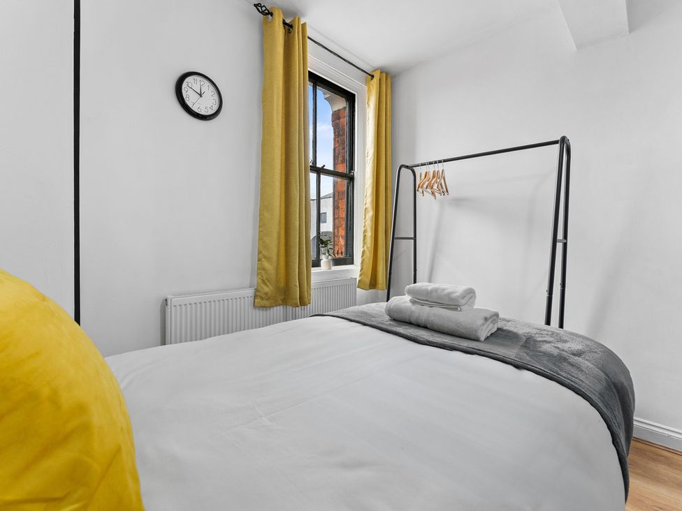 A bedroom with a bed and hanging rack at The Craftsman Birmingham City Apartment Birmingham