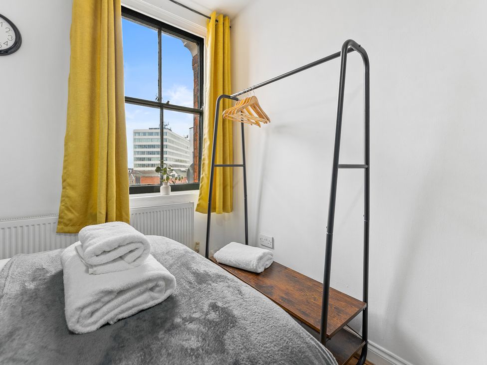 A bedroom with a window, towels on a bed and clothes hanger at The Craftsman Birmingham City Apartment Birmingham
