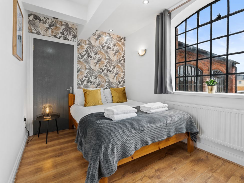 A bedroom with a bed, lamp, and window at The Craftsman Birmingham City Apartment Birmingham