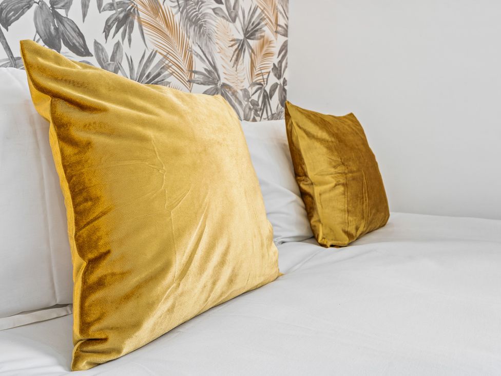 A bed with yellow pillows and patterned wallpaper at The Craftsman Birmingham City Apartment Birmingham