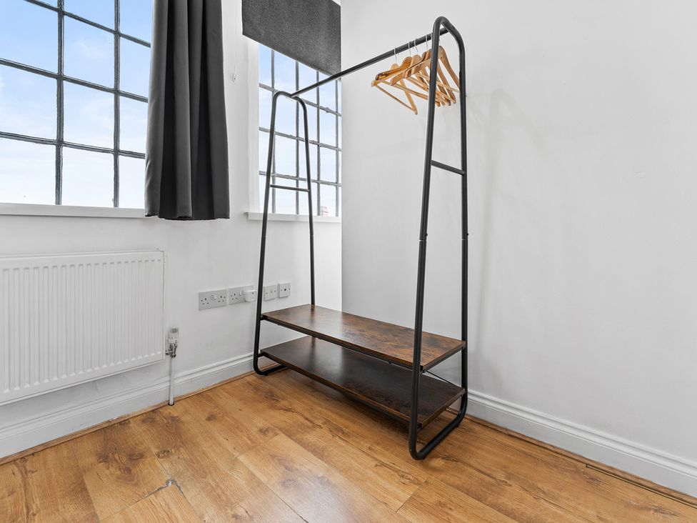 A clothes rack and wooden shelf in a bedroom at The Craftsman Birmingham City Apartment Birmingham