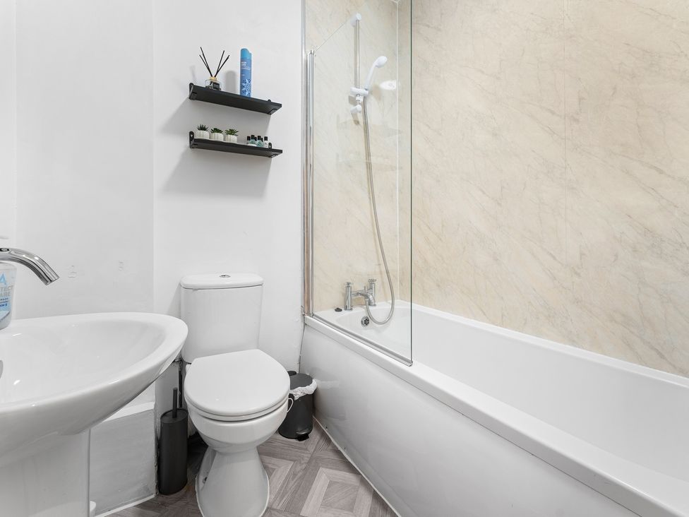 A bathroom with a bathtub, toilet, and washbasin at The Craftsman Birmingham City Apartment Birmingham