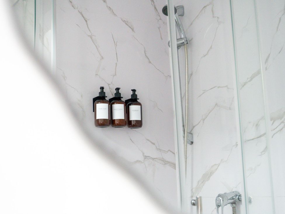 A shower with soap dispensers on a wall at The Craftsman Birmingham City Apartment Birmingham