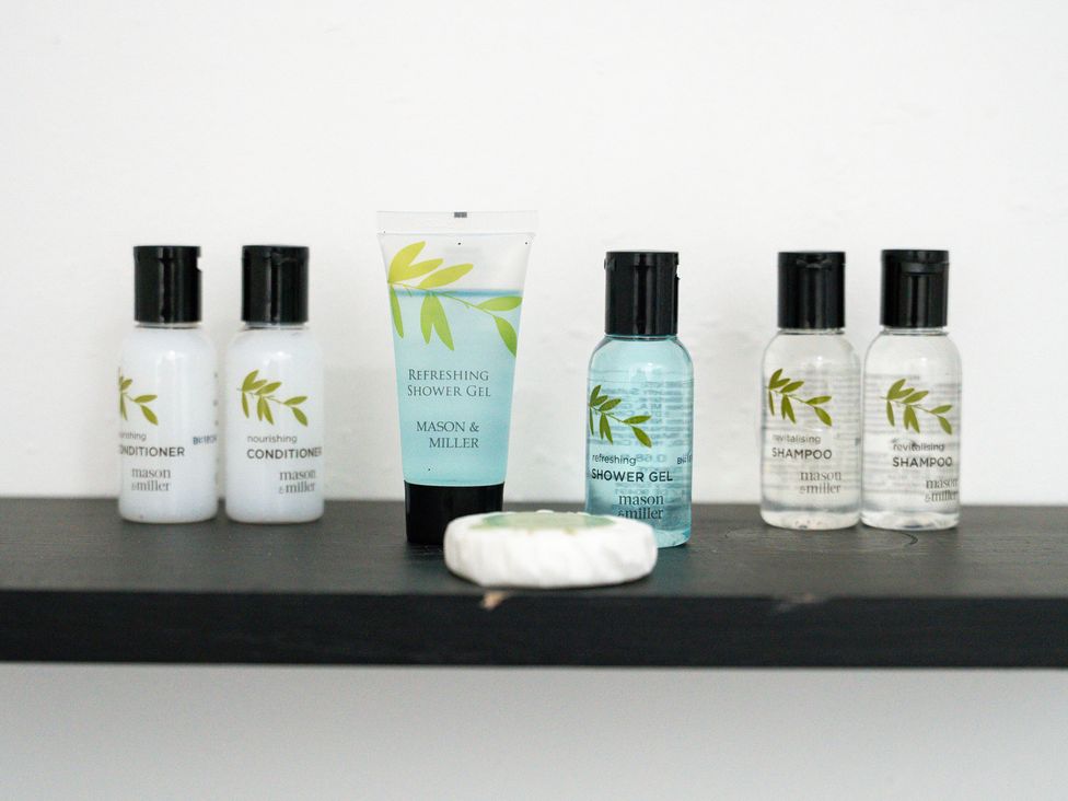 A collection of shampoo, conditioner, and shower gel on a shelf at The Craftsman Birmingham City Apartment Birmingham