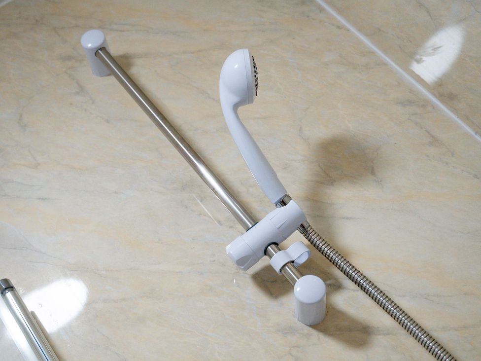 A showerhead mounted on a rail in a bathroom at The Craftsman Birmingham City Apartment Birmingham