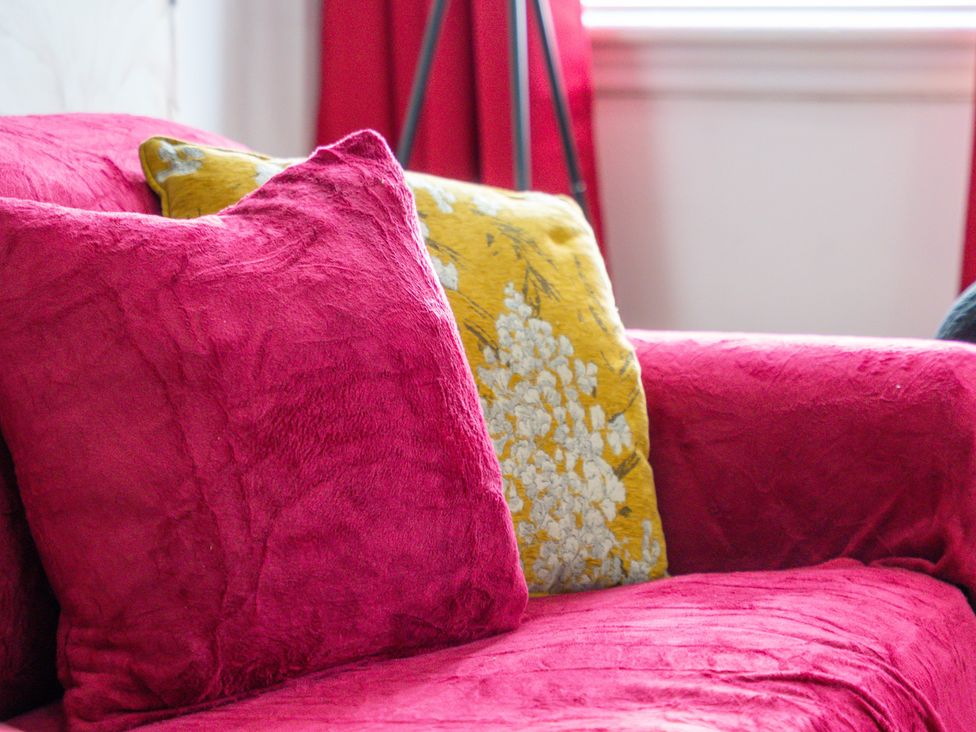 A couch with pink and yellow pillows at The Goldsmith Birmingham City Apartment Birmingham
