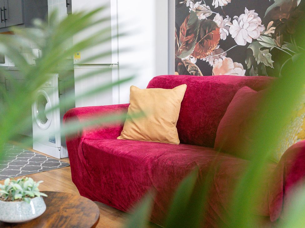 A couch with a pillow and a washing machine in the background at The Goldsmith Birmingham City Apartment Birmingham
