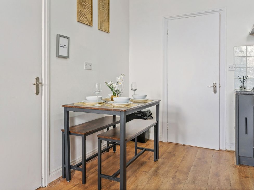 A dining table with benches and glasses at The Goldsmith Birmingham City Apartment in Birmingham
