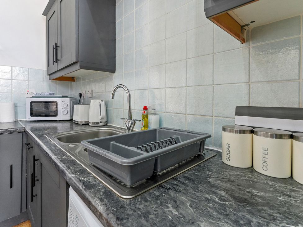 A kitchen with a sink, microwave, and storage containers at The Goldsmith Birmingham City Apartment in Birmingham