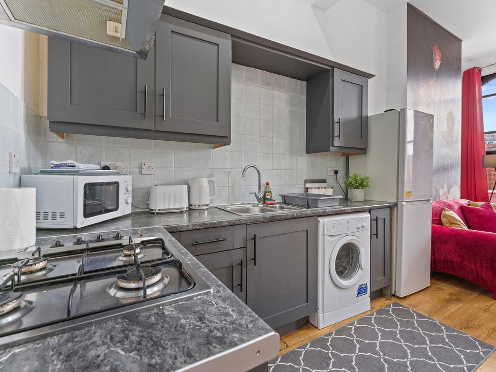 A kitchen with appliances and a washing machine at The Goldsmith Birmingham City Apartment Birmingham