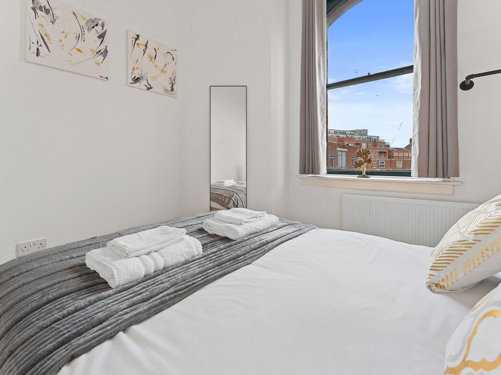 A bedroom with a bed and a mirror at The Goldsmith Birmingham City Apartment Birmingham