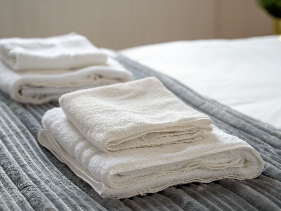 A stack of neatly arranged towels on a bed at The Goldsmith Birmingham City Apartment Birmingham