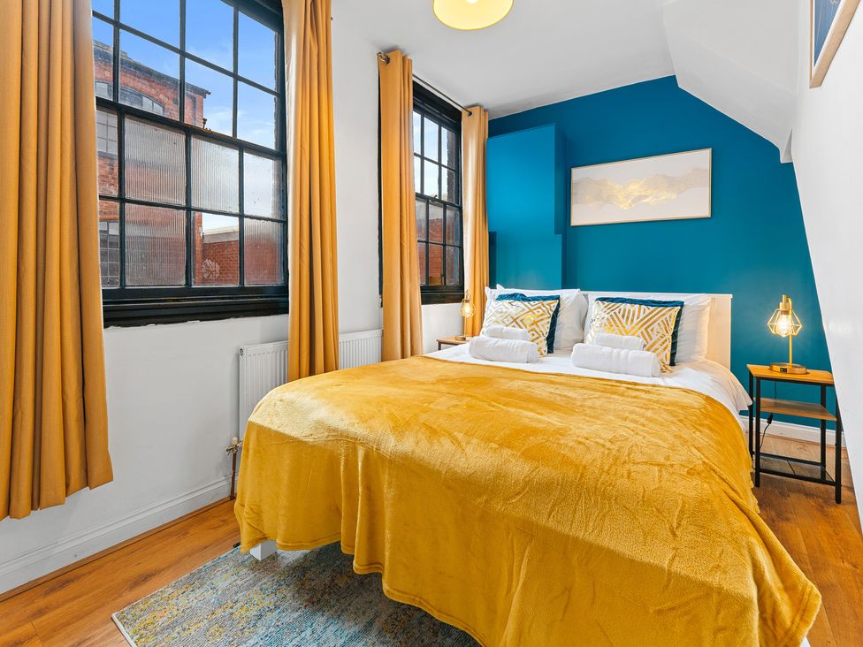 A bedroom with a bed and windows at The Goldsmith Birmingham City Apartment Birmingham