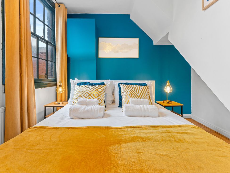 A bedroom with a bed, pillows, and nightstand at The Goldsmith Birmingham City Apartment Birmingham