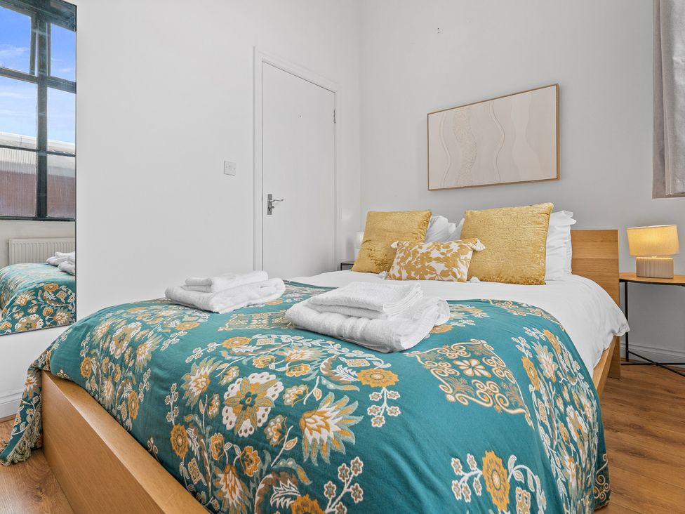 A bedroom with a bed and a lamp at The Goldsmith Birmingham City Apartment in Birmingham