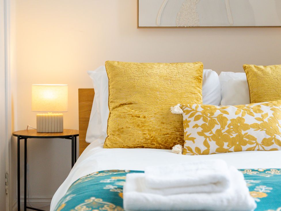 A bedroom with yellow cushions and a lamp at The Goldsmith Birmingham City Apartment Birmingham