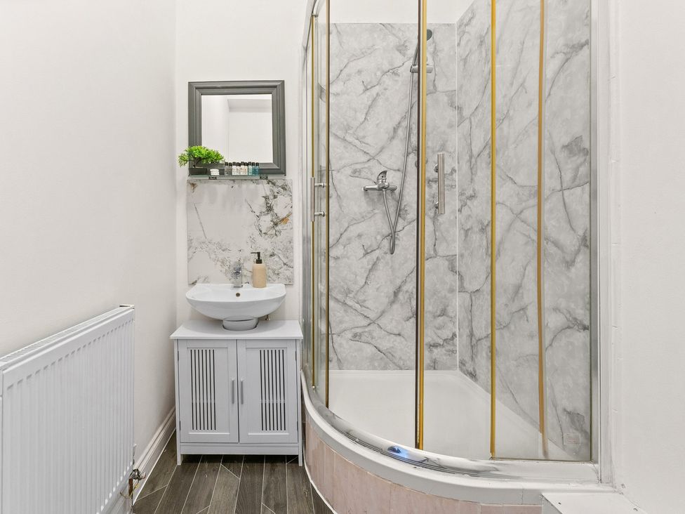 A bathroom with a shower, sink, and mirror at The Goldsmith Birmingham City Apartment Birmingham