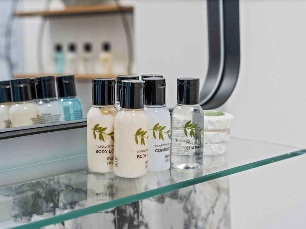 A collection of toiletries including body lotion, conditioner, and shampoo in a bathroom at The Goldsmith Birmingham City Apartment Birmingham