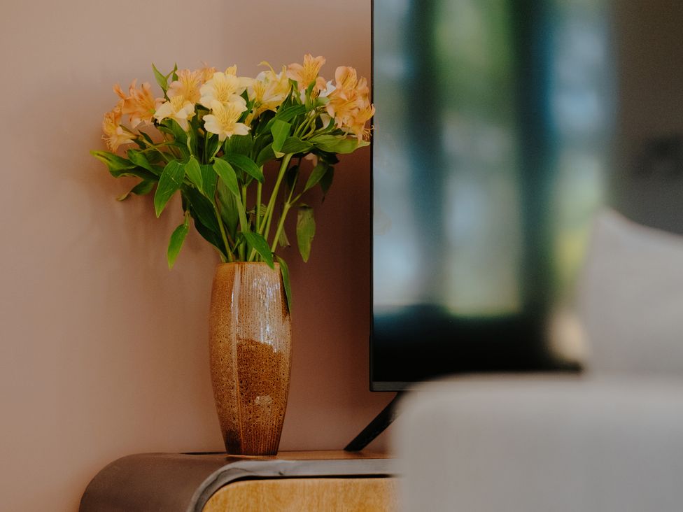 A flower vase with flowers next to a television at Baldslow Stables in Battle near Hastings