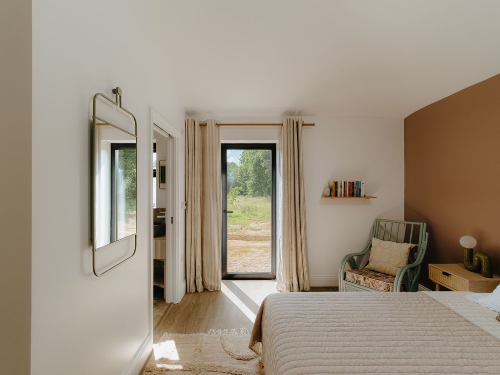 A bedroom with a bed, chair, and bookshelf at Baldslow Stables near Battle