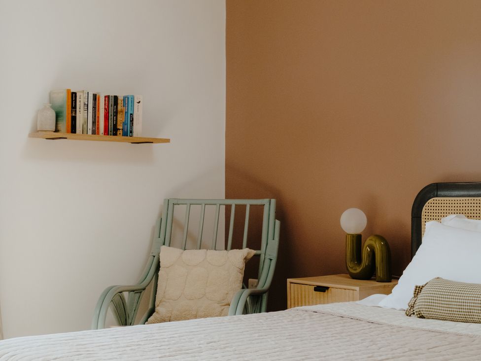A bedroom with books on a shelf and an armchair at Baldslow Stables in Battle near Hastings