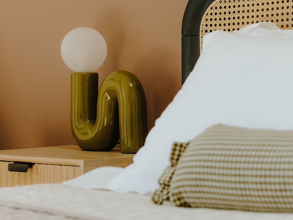 A bedside table with a lamp next to a bed in Baldslow Stables in Battle near Hastings