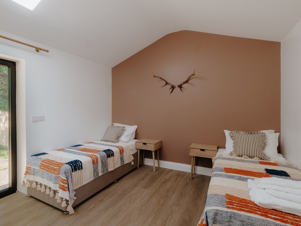 A bedroom with two single beds and two bedside tables at Baldslow Stables near Battle