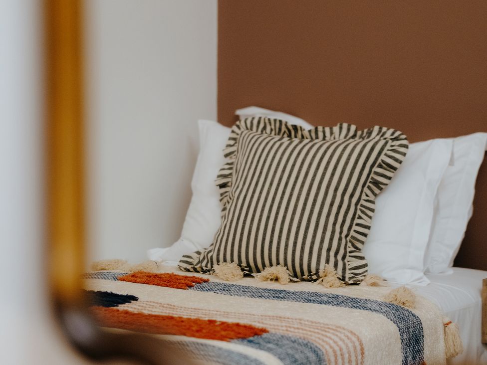 A bedroom with a striped pillow and a blanket at Baldslow Stables in Battle near Hastings